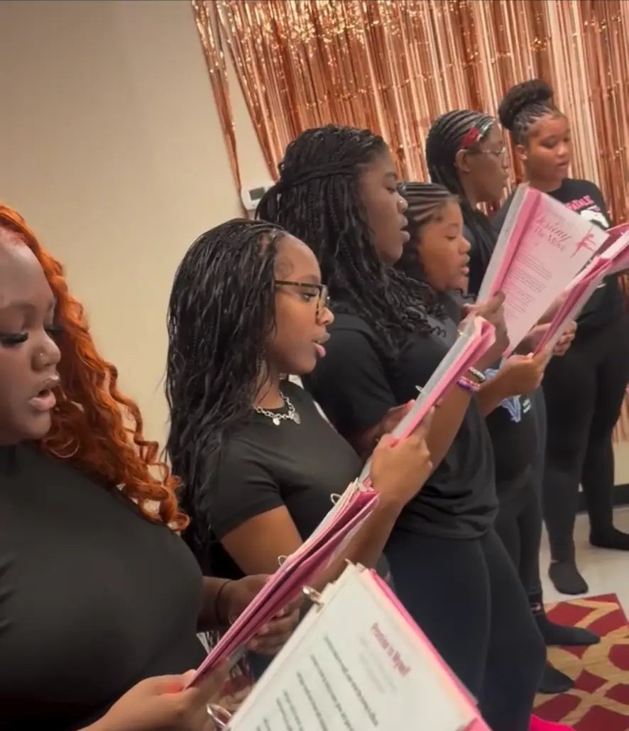 Girls standing in a row at an event, holding their workbooks open
